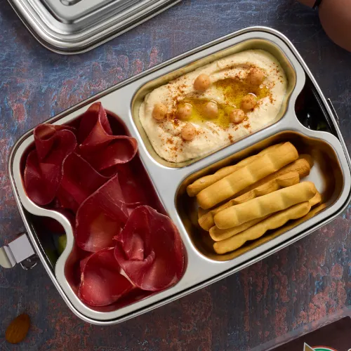 Insalata greca con bresaola, hummus e grissini in un porta pranzo